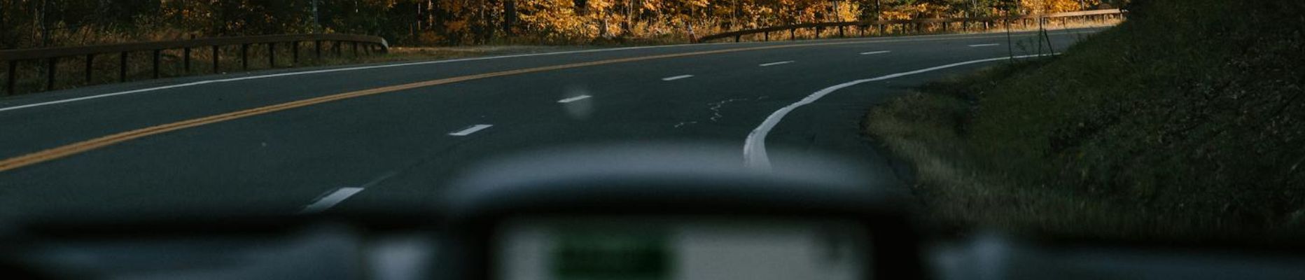 Modern car driving along curvy asphalt road amidst lush autumn trees in countryside on sunny day for blog on unhooking: ways to move forward in life