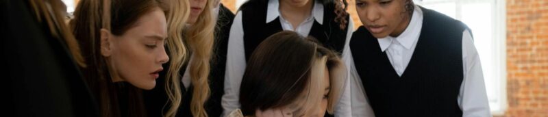 A diverse group of schoolgirls surrounding and staring at a classmate for blog on Are You looking at me? Overcoming Social anxiety