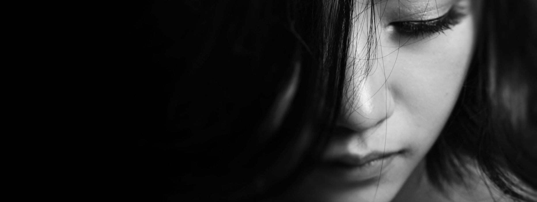 A black and white image of female face where half is covered by her hair to represent Treatment for Trauma