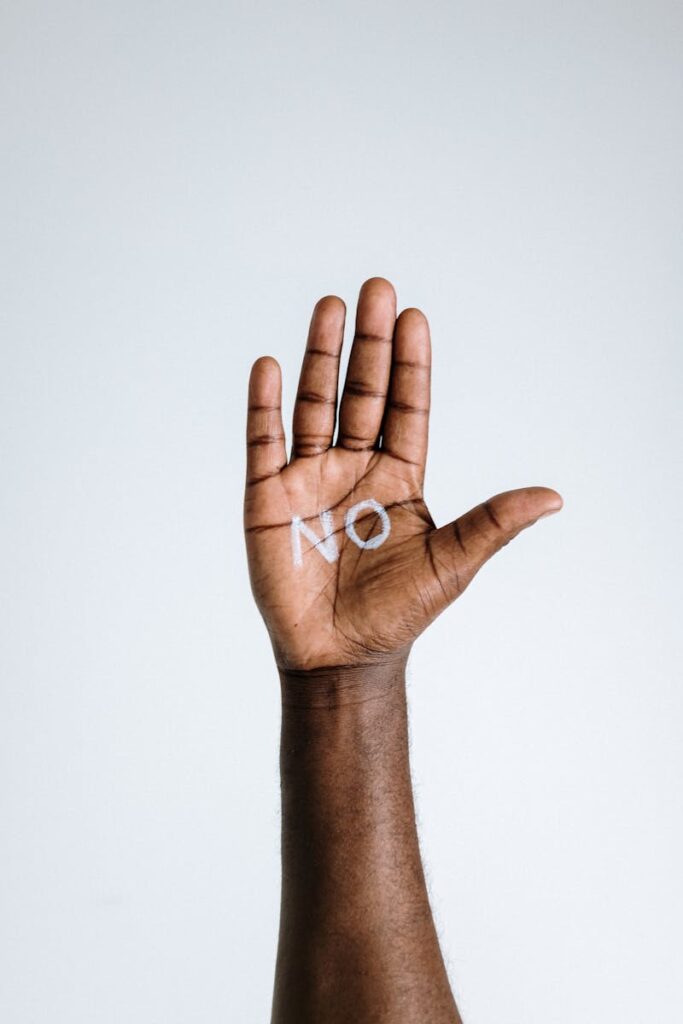 A hand with the word 'No' written on the palm, symbolizing refusal or denial for Hidden Signs & Costs of being a people pleaser blog post