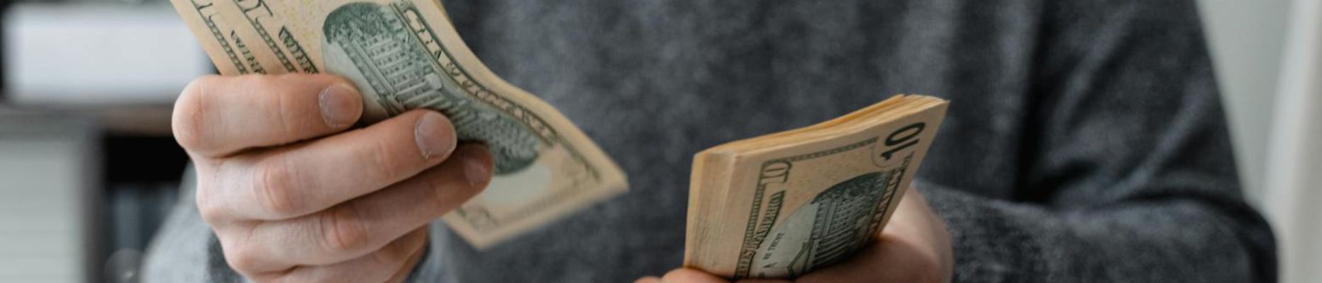 Close-up of person counting cash with a calculator and paperwork on a desk to represent budgeting for blog post about budgeting: 5 ways to improve your budget & decreased your stress