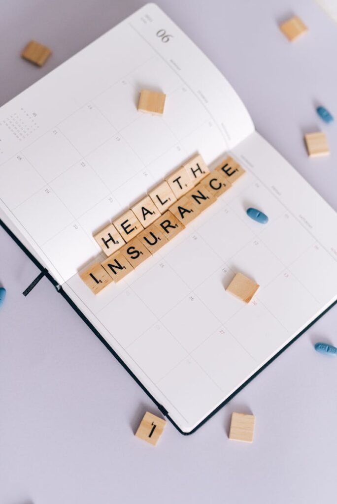 Flat lay of planner with 'Health Insurance' in Scrabble tiles, emphasizing medical insurance