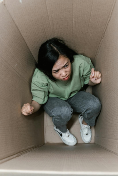 A woman feeling trapped inside a small cardboard box for Treatment for OCD page.