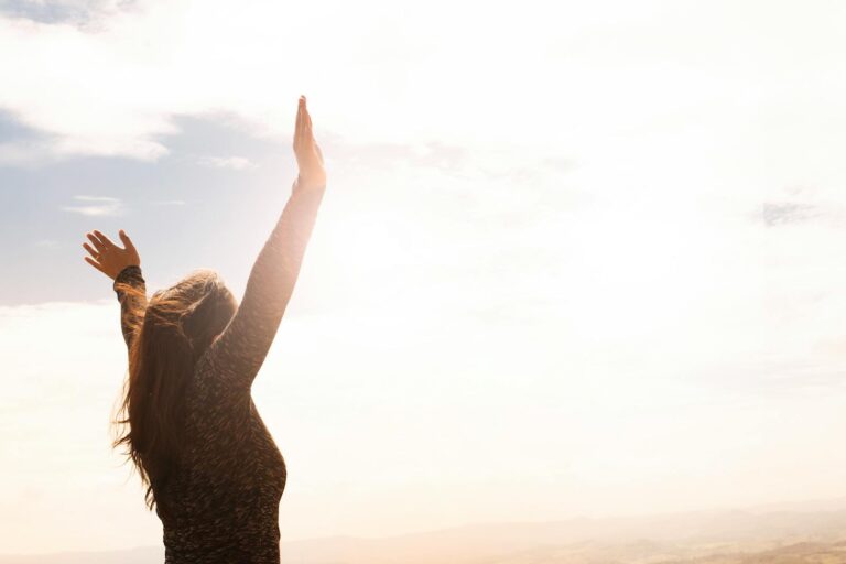 Photo by Daniel Reche A woman with raised arms enjoying the bright open sky in a serene outdoor setting for EMDR Intensive webpage