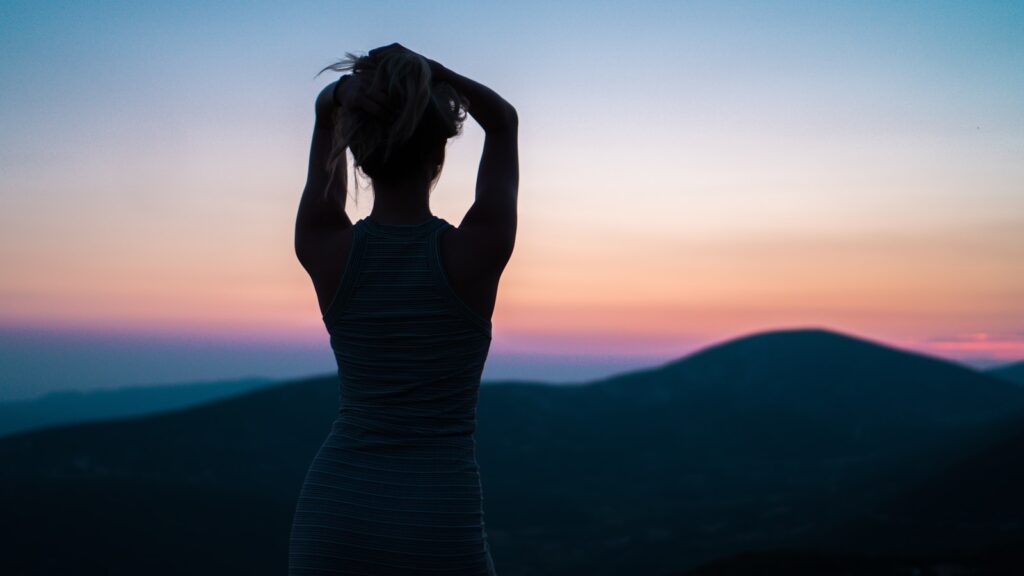 Photo by Vlad Gedroics silhouette of woman standing near mountain peak representing personal growth and healing through EMDR Intensive therapy for trauma an anxiety.
