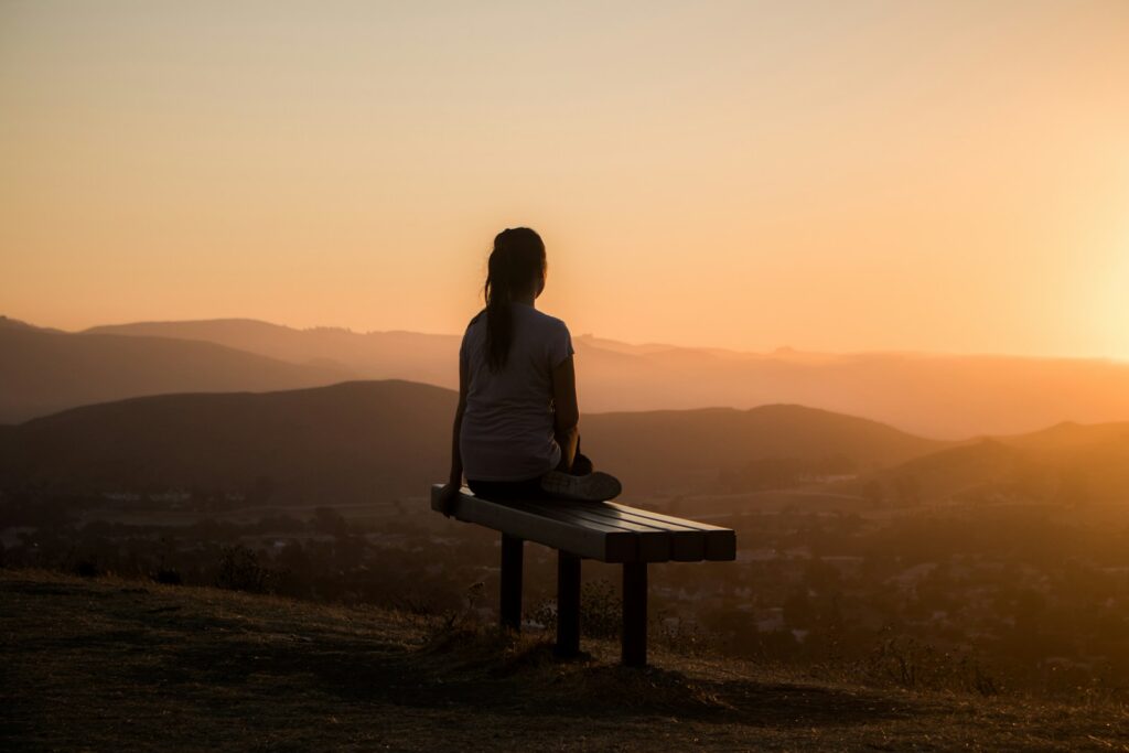 Photo by Sage Friedman woman sitting on bench over viewing mountain for my approach to trauma therapy webpage