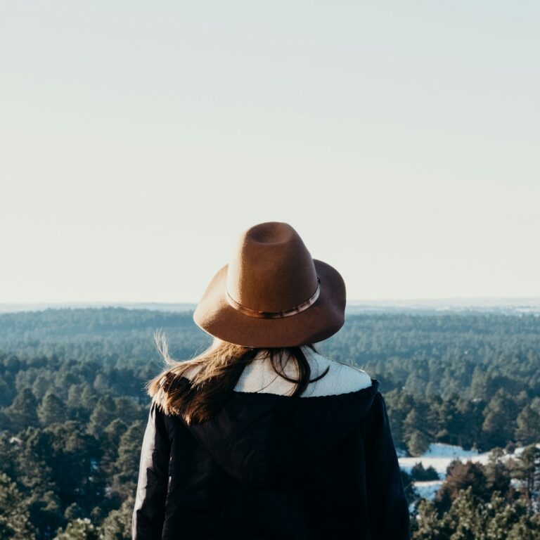 Photo by Noah Buscher woman standing on mountain with green trees for my approach to trauma therapy webpage