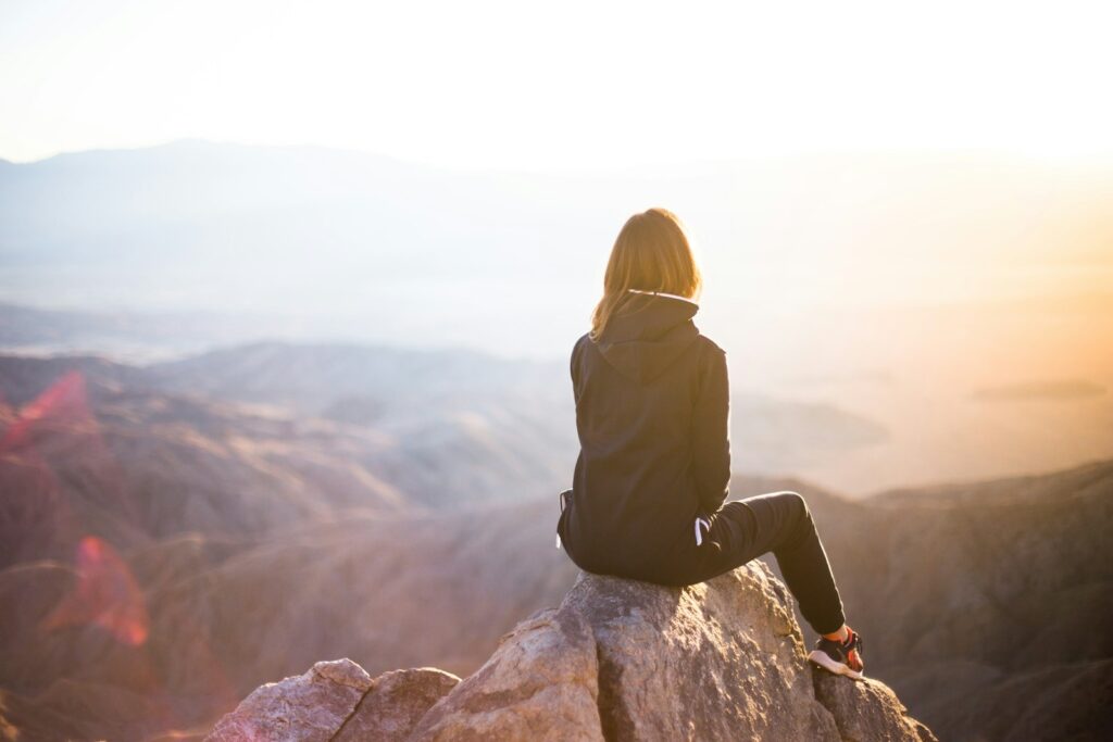 Photo by Denys Nevozhai Person sitting on top of gray rock overlooking mountain during daytime. Judy Wang offers trauma therapy using EMDR therapy in Maryland, Nevada & South Carolina.