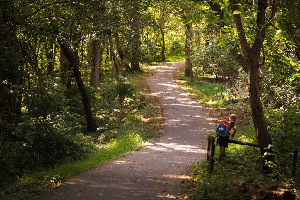 A kid with a colorful backpack explores a wooded trail in Bethesda, Maryland. Trauma Therapy in Bethesda, MD