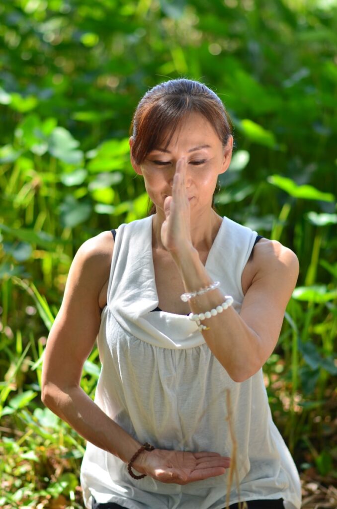 Photo by Hitomi Okushima A woman standing in a field of grass practicing deep breathing for social anxiety blog post