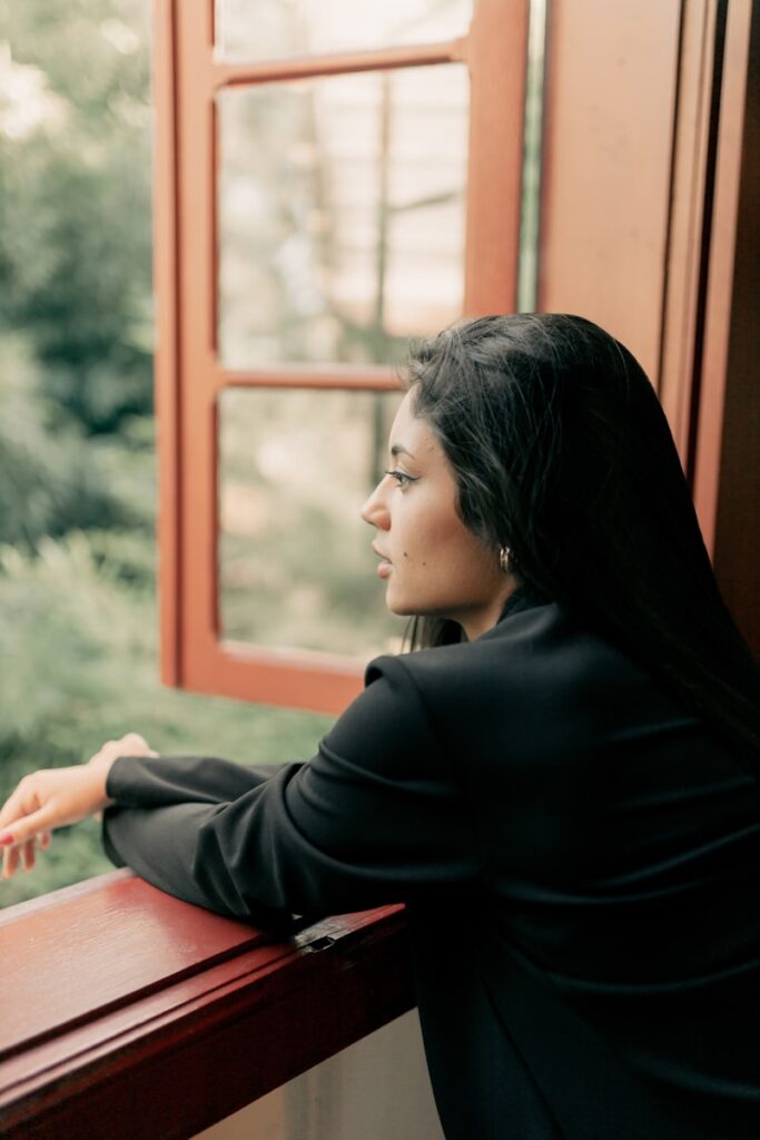Photo by Alexander Mass A woman gazes out a window at a forest, symbolizing the calm and reflection that EMDR Intensive therapy can bring for trauma and anxiety.